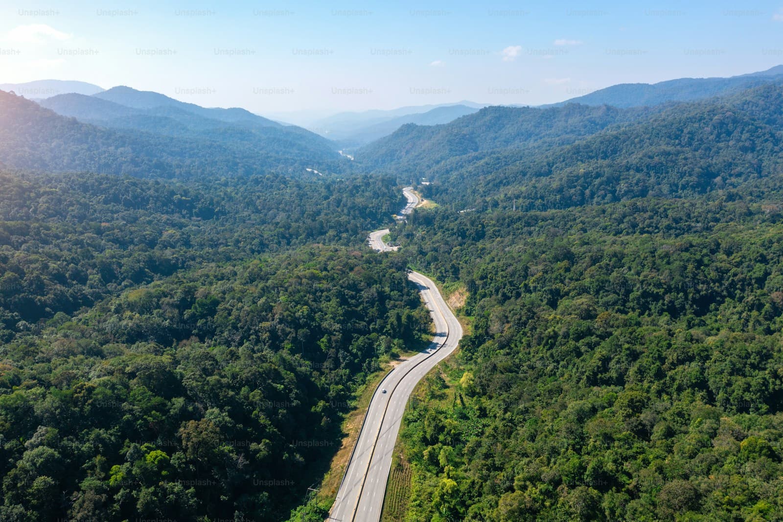 Aerial view of a highway snaking through forested mountains and a deep valley